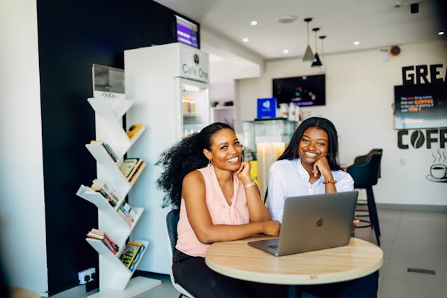 Two women sitting in front of the laptop